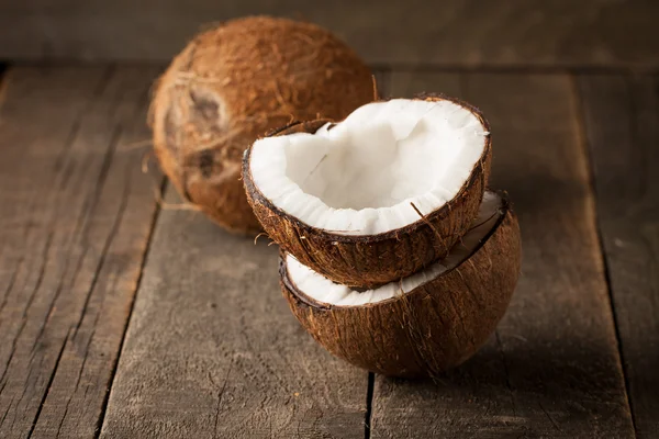 Noix de coco mûre demi coupée sur un fond en bois. Noix de coco demi-coupée mûre avec du lait sur un fond en bois — Photo
