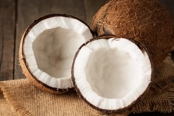 Olgun yarı ahşap bir arka plan üzerine Hindistan cevizi kesti. Olgun yarı ahşap bir arka plan üzerine Hindistan cevizi sütü ile kesmek