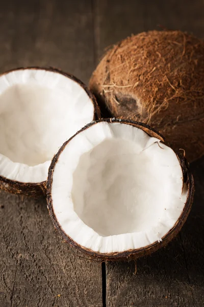 Rijpe halve cut kokosnoot op een houten achtergrond. Rijpe halve cut kokosnoot met melk op een houten achtergrond — Stockfoto