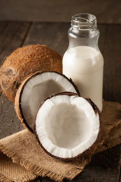 Rijpe halve cut kokosnoot op een houten achtergrond. Rijpe halve cut kokosnoot met melk op een houten achtergrond — Stockfoto