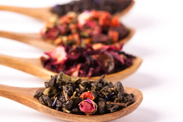 Torra te i träskedar på trä rustika bakgrund. Bladen av rött, grönt och svart te. Makro foto. Rustik stil och koncept. — Stockfoto