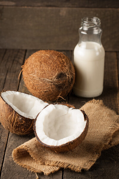 Ripe half cut coconut on a wooden background. Ripe half cut coconut with milk on a wooden background