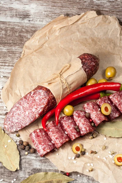 Salami italiano con aceitunas y especias sobre fondo de madera — Foto de Stock