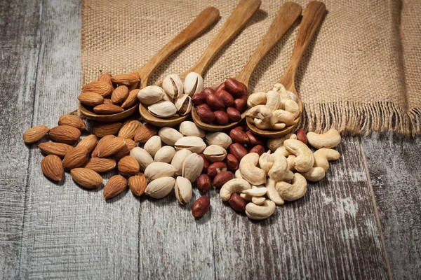 Nueces de mezcla saludable sobre fondo de madera. Almendras, avellanas, anacardos, cacahuetes, nueces brasileñas — Foto de Stock