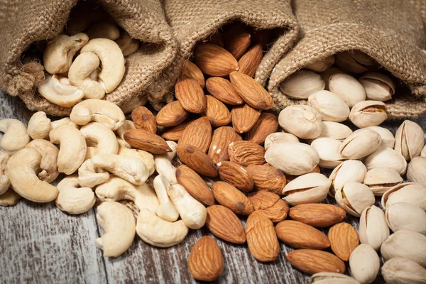 Nueces de mezcla saludable sobre fondo de madera. Almendras, avellanas, anacardos, cacahuetes, nueces brasileñas — Foto de Stock