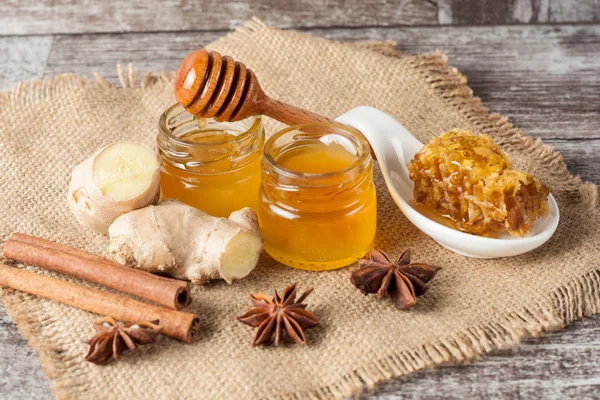 Μέλι στάζει από μια κουτάλα ξύλινη μέλι σε ένα βάζο σε ξύλινα γκρι φόντο για ρουστίκ — Φωτογραφία Αρχείου