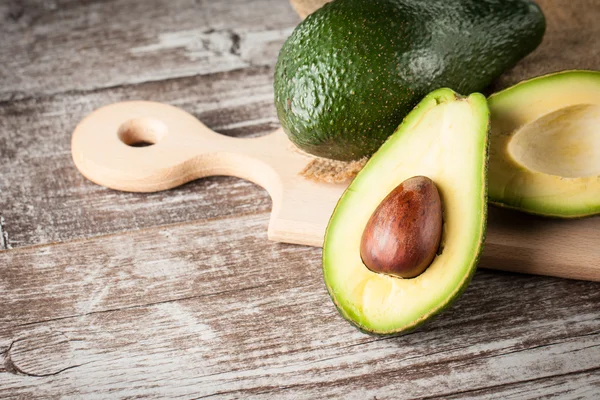 Close-up of an avocado and avocado oil on wooden table. Healthy food concept. — Stock Photo, Image