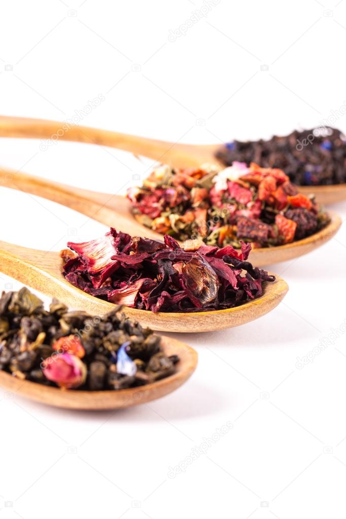 Dry tea in wooden spoons on wooden rustic background. Leaves of red, green and black tea. Macro photo. Rustic style and concept.