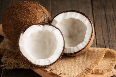 Olgun yarım Hindistan cevizi ahşap bir arka plan üzerinde kesmek..