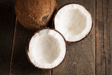 Olgun yarım Hindistan cevizi ahşap bir arka plan üzerinde kesmek..