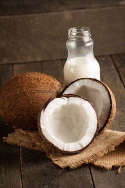 Olgun yarım Hindistan cevizi ahşap bir arka plan üzerinde kesmek..