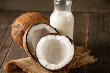 Olgun yarım Hindistan cevizi ahşap bir arka plan üzerinde kesmek..