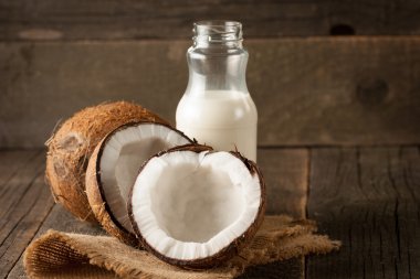 Olgun yarım Hindistan cevizi ahşap bir arka plan üzerinde kesmek..