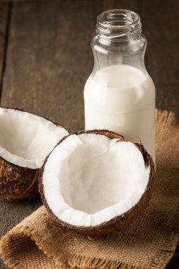 Olgun yarım Hindistan cevizi ahşap bir arka plan üzerinde kesmek..