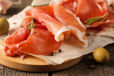 prosciutto ile karışık zeytin ve ahşap kesme tahtası üzerinde kırmızı biber ince dilim closeup