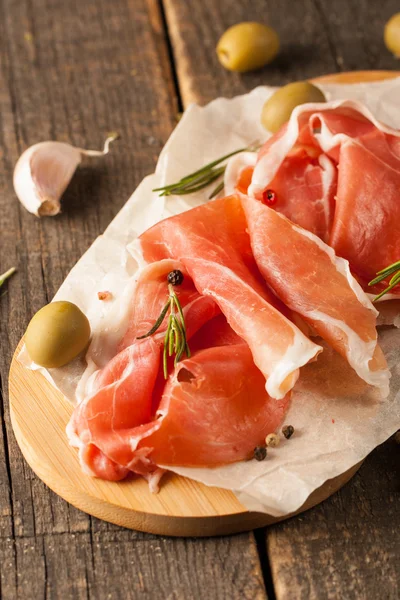 prosciutto ile karışık zeytin ve ahşap kesme tahtası üzerinde kırmızı biber ince dilim closeup
