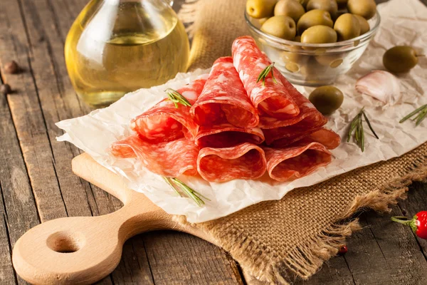 Salame italiano com azeitonas e especiarias em fundo de madeira — Fotografia de Stock