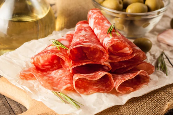 Salami italiano con aceitunas y especias sobre fondo de madera — Foto de Stock