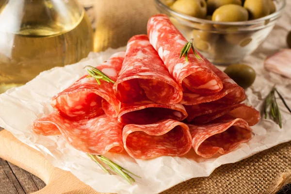 Salame italiano com azeitonas e especiarias em fundo de madeira — Fotografia de Stock