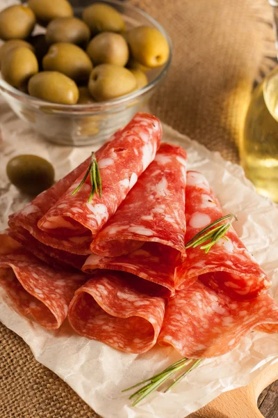 Salame italiano com azeitonas e especiarias em fundo de madeira — Fotografia de Stock