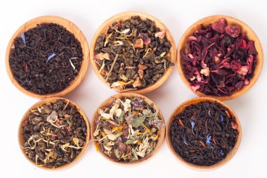 Ahşap Kaplamalar, beyaz zemin üzerine kuru çay. Kırmızı, yeşil ve siyah çay yaprakları. Makro fotoğraf.