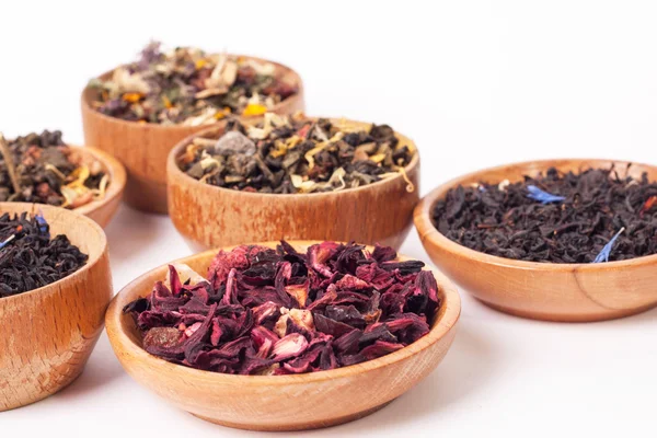 Trockener Tee in Holztellern, auf weißem Hintergrund. Blätter von rotem, grünem und schwarzem Tee. Makrofoto. — Stockfoto
