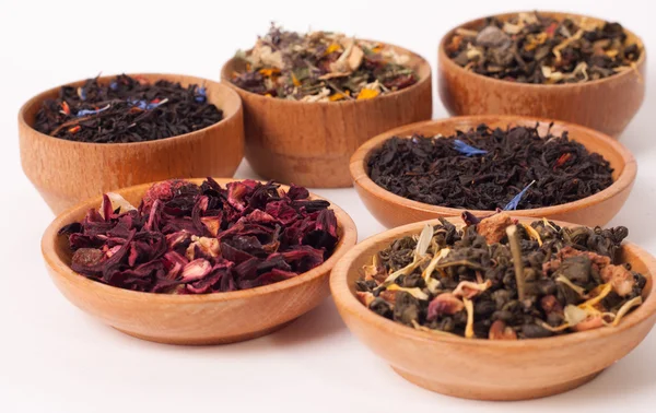 Dry tea in wooden plates, on white background. Leaves of red, green and black tea. Macro photo. — Stock Photo, Image