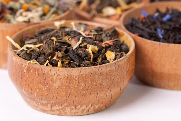 Dry tea in wooden plates, on white background. Leaves of red, green and black tea. Macro photo. — Stock Photo, Image