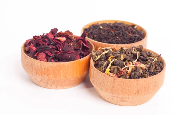 Trockener Tee in Holztellern, auf weißem Hintergrund. Blätter von rotem, grünem und schwarzem Tee. Makrofoto. — Stockfoto