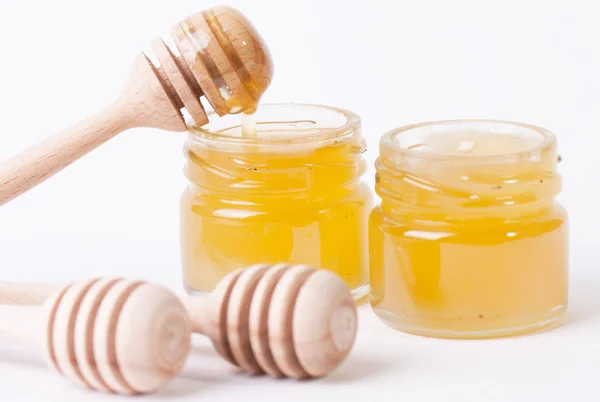 Miel goteando de un tarro de miel de madera aislado sobre fondo blanco —  Fotos de Stock
