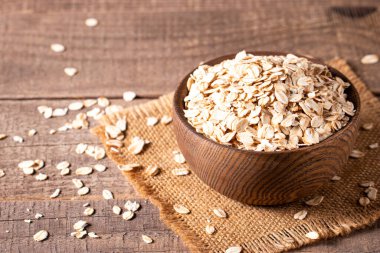 Ahşap bir arka planda tahta bir kasede çiğ yulaf. Organik gıda konsepti.