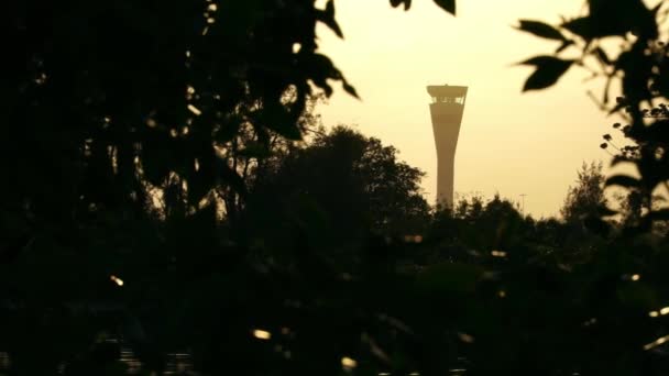 Backlit silhouette of Air Traffic Control tower, green trees in foreground. Brisbane, Queensland, Australia 12 21 2020 – stockvideo