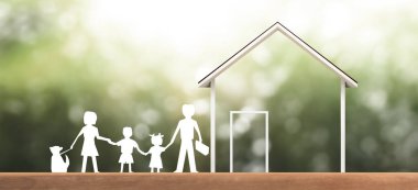 Çatı altında beyaza boyanmış ev modeli, koruma altındaki kağıt zinciri ailesini gösteriyor