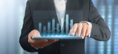 İşadamı, elinde tabletle iş yerinde grafik büyümesi ve grafik artışı planlıyor