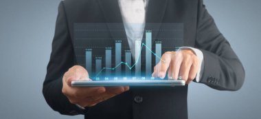 İşadamı, elinde tabletle iş yerinde grafik büyümesi ve grafik artışı planlıyor