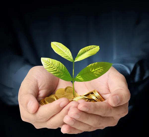 Man holding plant sprouting from a handful of coins — Stock Photo, Image