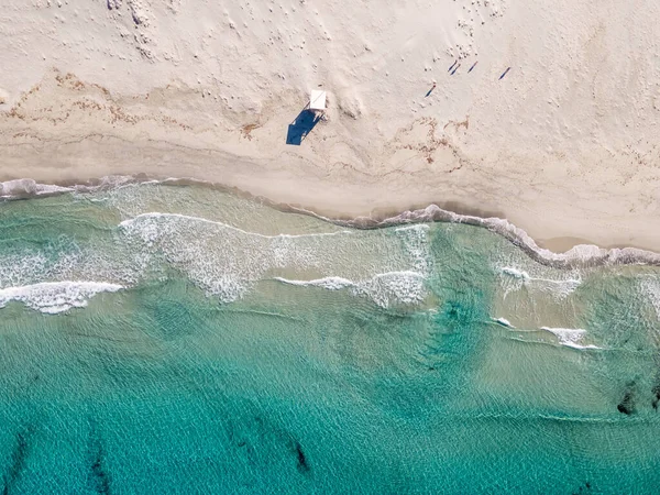 Birds-eye view of the waves of the turquoise mediterranean washing onto the white sandy beach of Ostriconi in the Balagne region of Corsica