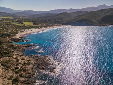 Korsika 'nın Balagne bölgesindeki Ostriconi' nin beyaz kumlu plajına vuran turkuaz Akdeniz manzarası