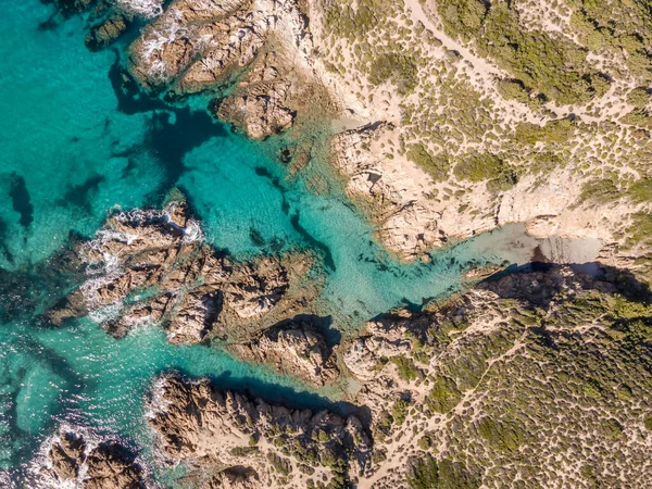 Korsika 'nın Balagne bölgesinde Ostriconi yakınlarında gözlerden uzak bir kayalık koyda küçük kumlu bir sahil ve turkuaz bir Akdeniz manzarası.