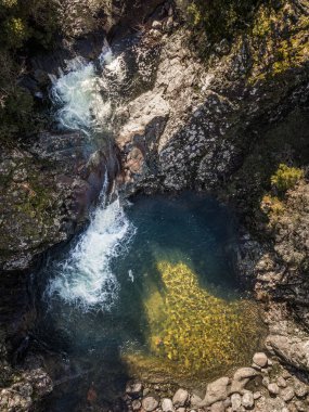 Korsika 'daki Pirio' daki temiz bir havuza dökülen bir dağ deresinin havadan görüntüsü.