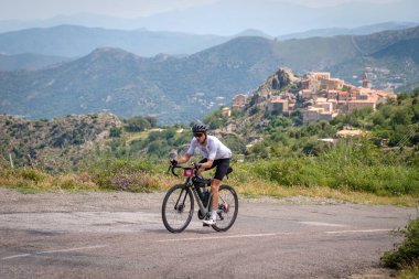 Speloncato, Korsika, Fransa - 9 Haziran 2021: Speloncato köyünde 780 km gittikten sonra Nico Faure 2021 Bisikletçi Korsika yarışında yarışıyor. Bisikletçi Korsika, adayı desteksiz bir şekilde çevreleyen yıllık 1000 kilometrelik bir dayanıklılık bisikleti etkinliğidir..
