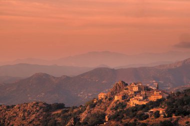 Evening sunshine on the ancient mountain village of Speloncato in the Balagne region of Corsica with Cap Corse in the distance
