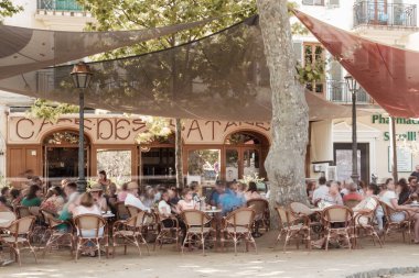 L 'Ile Rousse, Corsica, Fransa - 19 Ağustos 2021: Tatilciler Korsika' nın Balagne bölgesindeki L 'ile Rousse' daki Cafe des Platanes 'in önünde dinleniyorlar