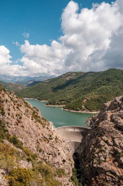 Korsika 'daki Tolla Gölü' ndeki baraj duvarı kayalık kayalıklarla ve uzak dağlarla çevrili çam ormanlarıyla çevrili.