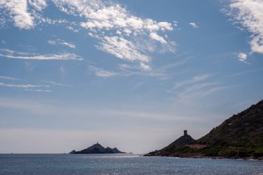 Korsika 'da Ajaccio yakınlarındaki Les Iles Sanguinaires' in Ceneviz kulesi ve deniz feneri mavi bir öğleden sonra gökyüzüne karşı siluetlendi.