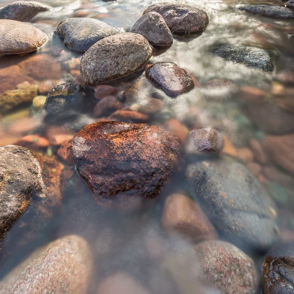 Rocas en un arroyo cristalino que fluye rápido — Foto de Stock