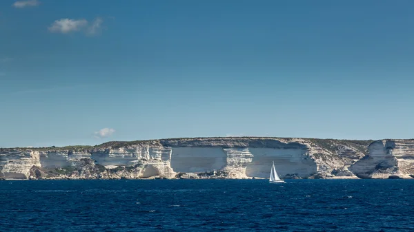 Sailing boat against white cliffs near Bonifacio in Corsica — Stock Photo, Image