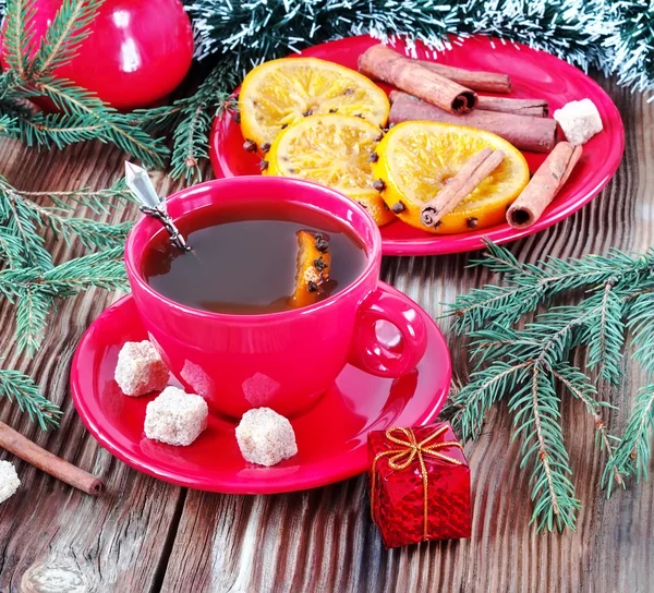 Tea in a red mug with cinnamon and oranges — Stock Photo, Image