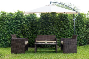 Set of rattan garden furniture under a big garden umbrella clipart
