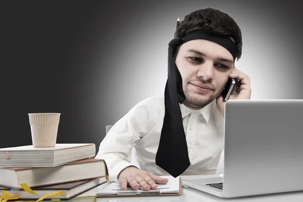 Hard working,businessman with big head on office desk ,on dark background — Stock Photo, Image